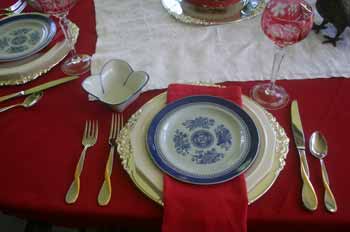 A silver charger, white plate, red napkin and Spode Blue Fitzgerald plate on top make up the layers.